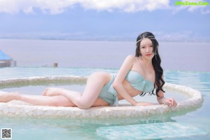 A woman in a blue bikini standing by a pool.