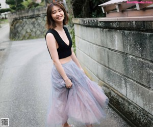 A woman in a black top and a gray tulle skirt crouching on the ground.