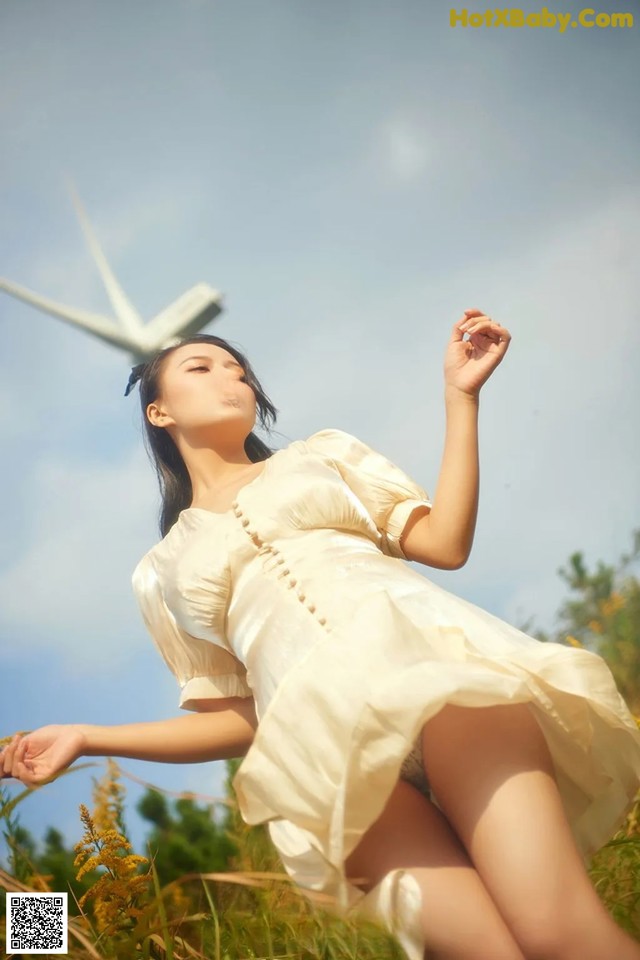 A woman in a white dress standing in a field.