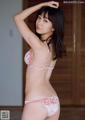 A woman in a pink lingerie sitting on a bed.