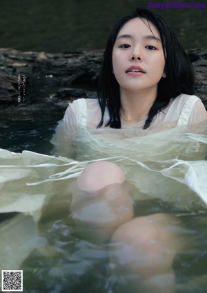 A woman in a green dress standing in the water.