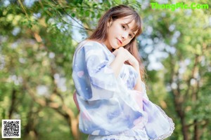 A woman sitting on the grass holding an umbrella.