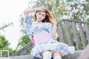 A woman in a blue and pink kimono sitting on a bench.