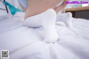 A young woman in a school uniform sitting on a bed.