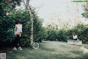 A woman wearing a face mask standing in front of a fence.
