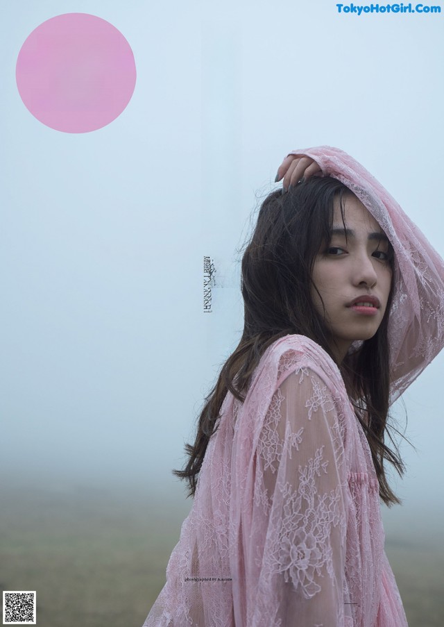 A woman in a pink dress standing in a field.