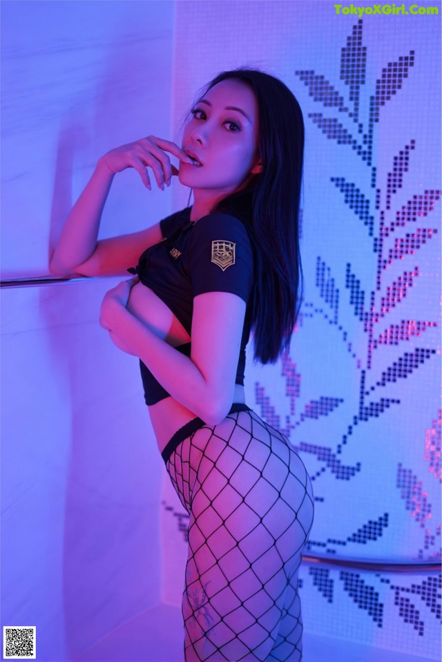 A woman in fishnet stockings leaning against a wall.