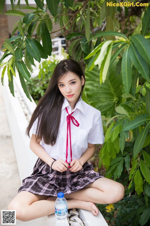 A woman in a school uniform sitting on a ledge.