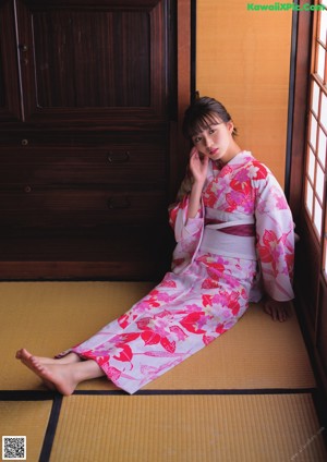 A woman in a pink kimono laying on the floor.