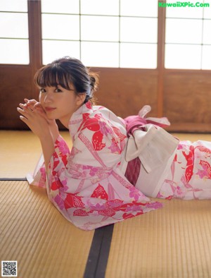 A woman in a pink and white kimono posing for a picture.