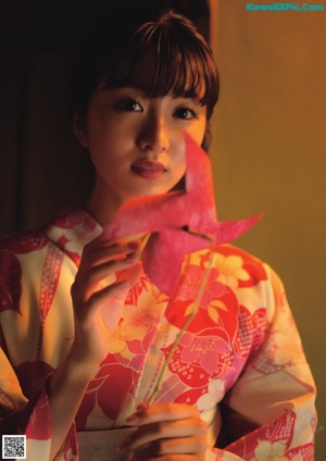 A woman in a pink and white kimono posing for a picture.