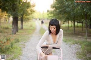 A woman pushing a shopping cart down a dirt road.