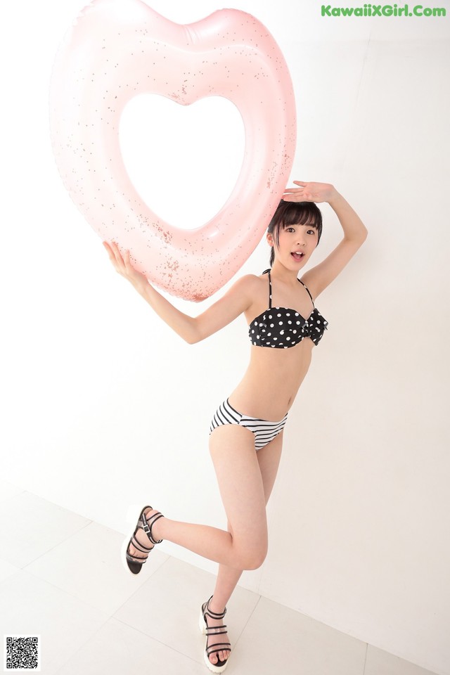 A woman in a bikini holding a heart shaped inflatable ring.