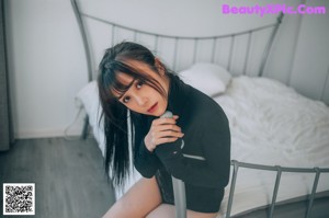 A woman in a black bodysuit posing in front of a window.