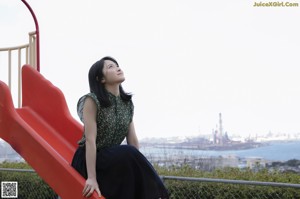 A woman in a green dress looking up at the sky.