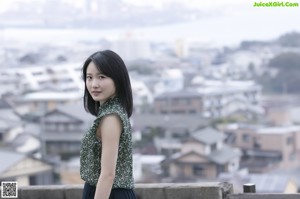 A woman in a green dress looking out over a city.