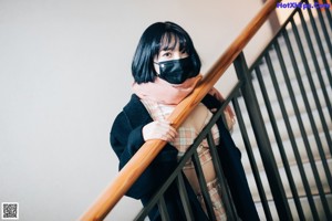 A woman wearing a face mask standing on a set of stairs.