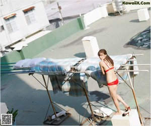 A woman in a red bikini holding a red and white towel.