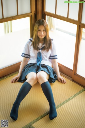 A woman in a blue and yellow dress laying on a bed.