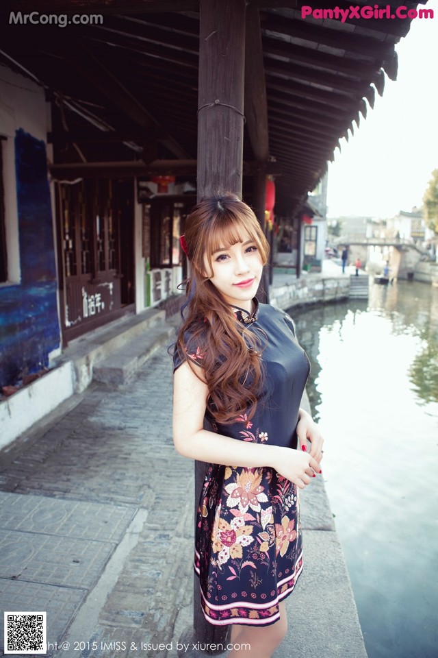A woman in a black dress standing next to a river.