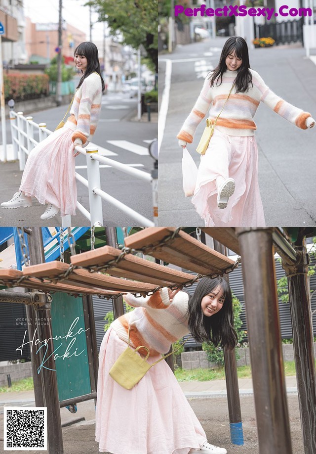 A woman in a pink skirt and a striped sweater is posing for a picture.