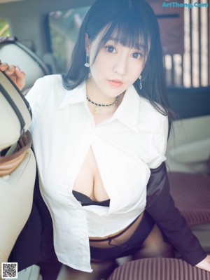 A woman in a black skirt and white shirt sitting in a car.