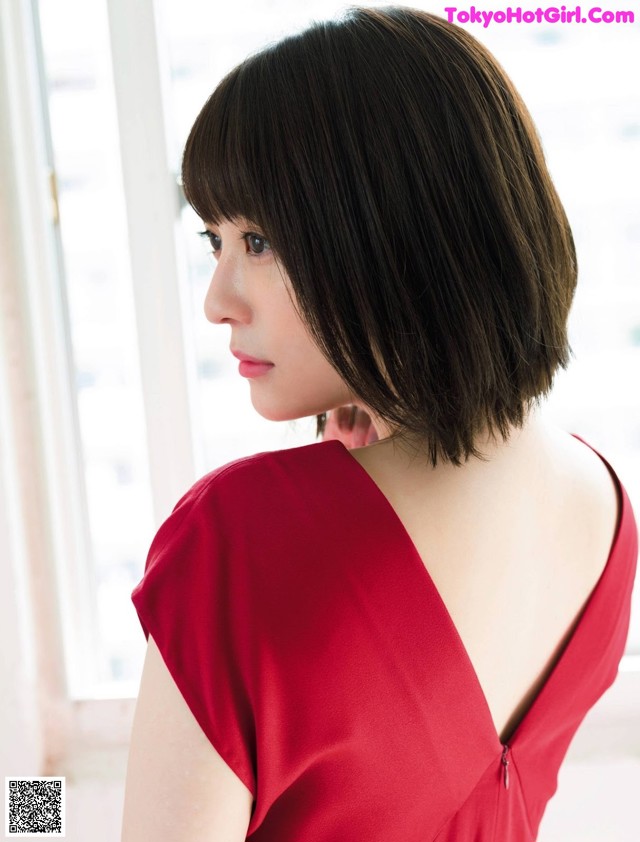 A woman in a red dress looking out a window.