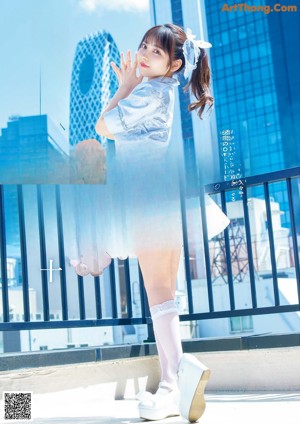 A young girl in a blue dress sitting on the floor.