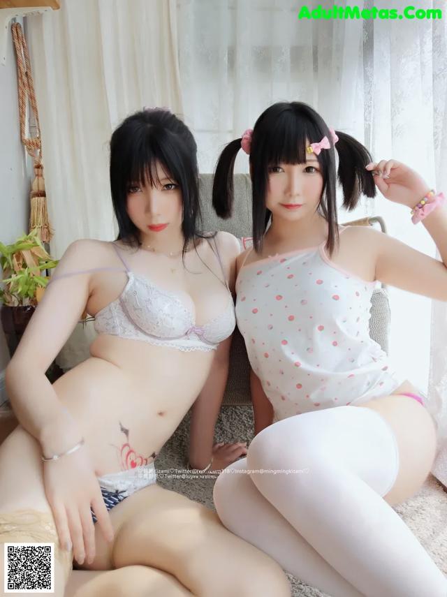 Two asian women in lingerie sitting on a bed.