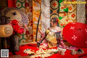 A woman in a kimono holding a cat mask.