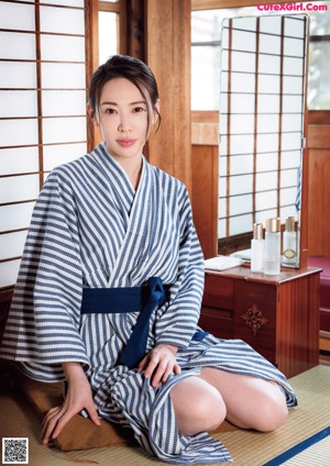 A woman in a blue and white striped kimono sitting on the floor.