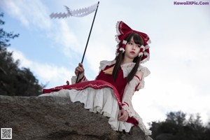 A woman in a red and white dress holding a fan.