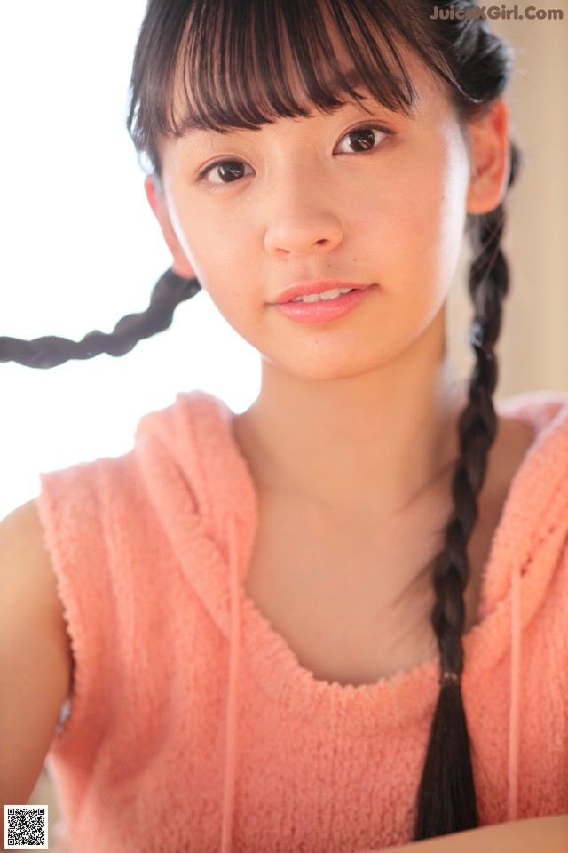 A young woman with long black hair in a pink hoodie.