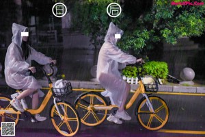 A couple of people riding bikes down a street at night.