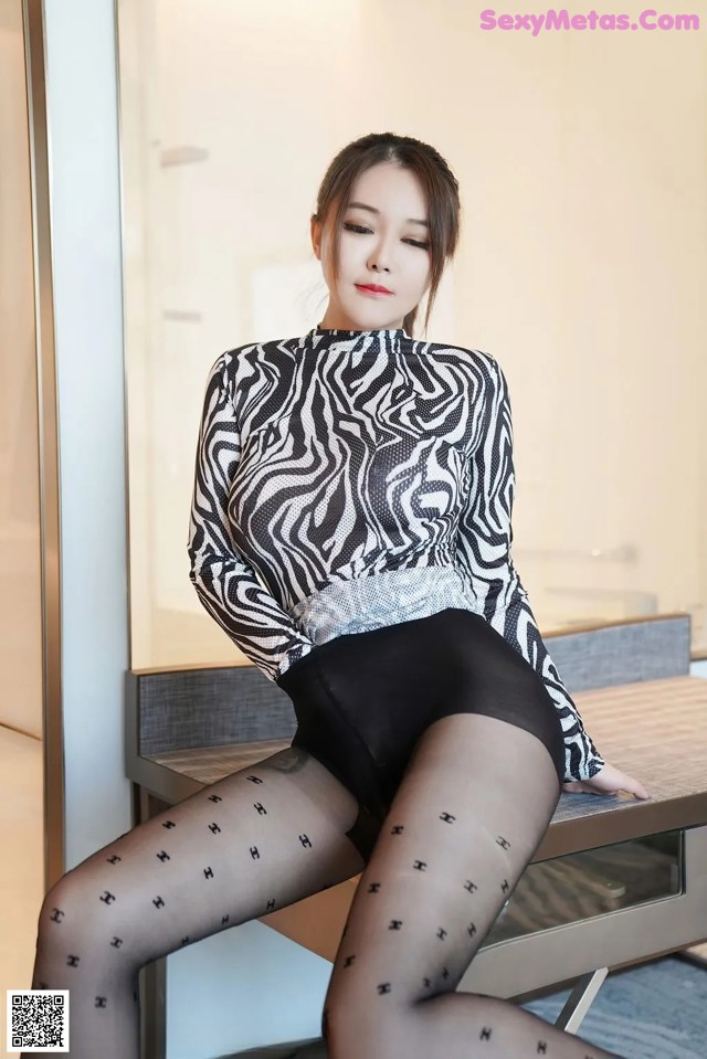 A woman sitting on top of a table wearing black stockings.