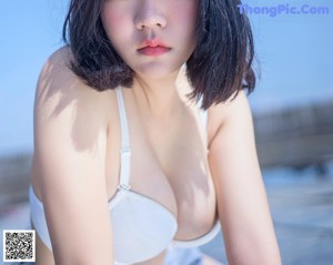 A woman in a white bra is posing for the camera.