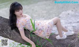 A woman sitting on a blanket in the grass.