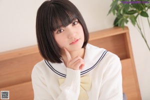 A woman in a school uniform standing in front of a window.