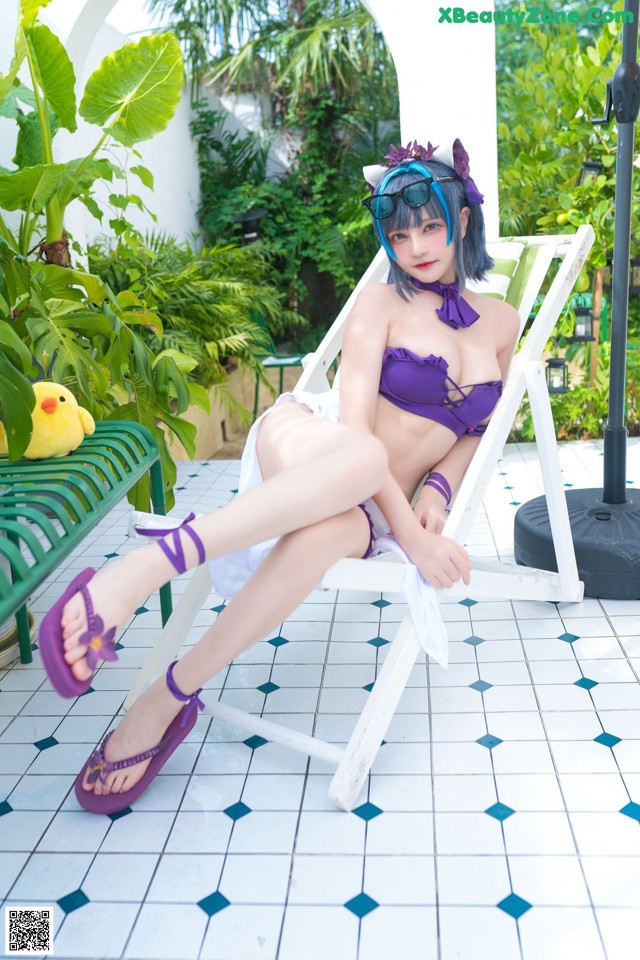 A woman in a purple bikini sitting on a white chair.