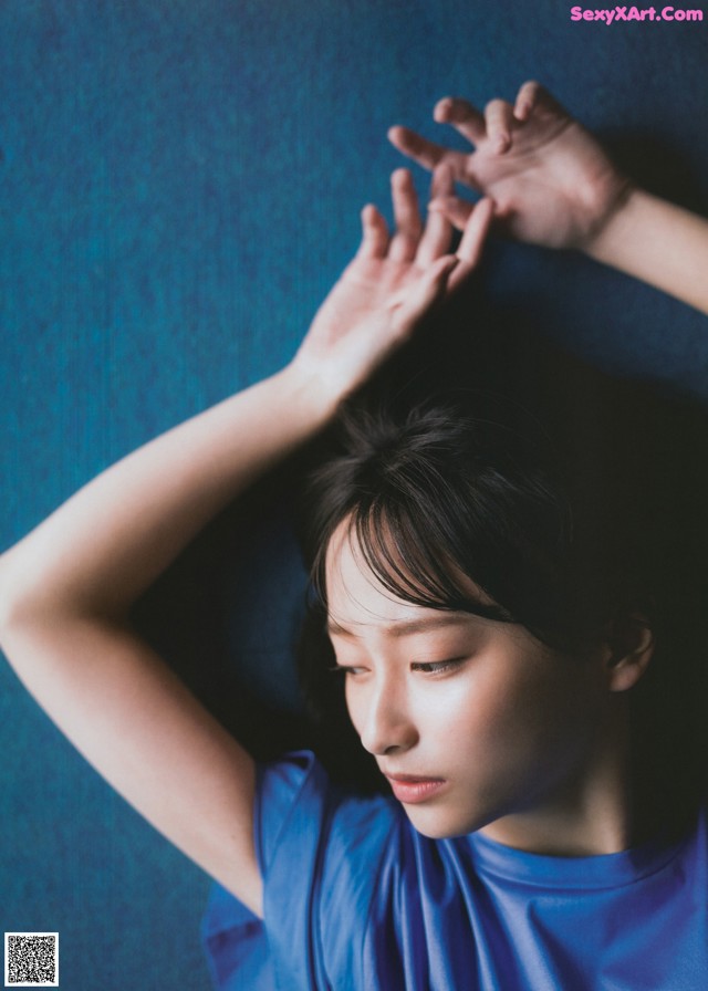 A woman in a blue dress laying on a blue surface.