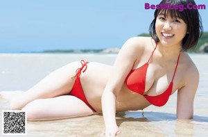 A woman in a red bikini laying on the beach.