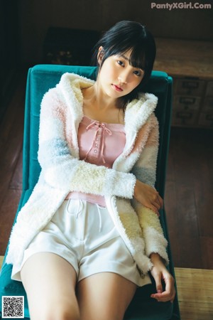 A woman in a pink top and white skirt posing for a picture.