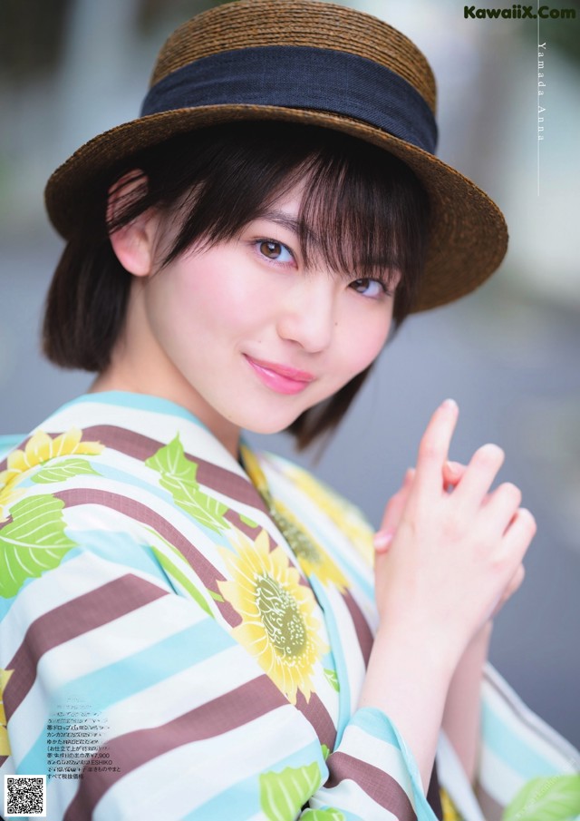 A woman in a kimono and a straw hat posing for a picture.