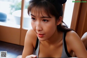 A woman standing in front of a window next to a fan.